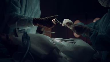 <strong>外科</strong>医生团队手缝合切口医疗西装黑暗操作房间特写镜头